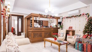 A cozy living room with a sofa, armchair, and a coffee table. There is a Christmas tree and a fireplace.