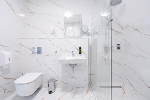 Un baño moderno con inodoro, lavamanos y ducha.