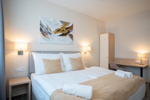 A hotel room with a bed, two bedside lamps, a wall-mounted painting, and a mirror. - Kikelet Club Hotel (Miskolc)