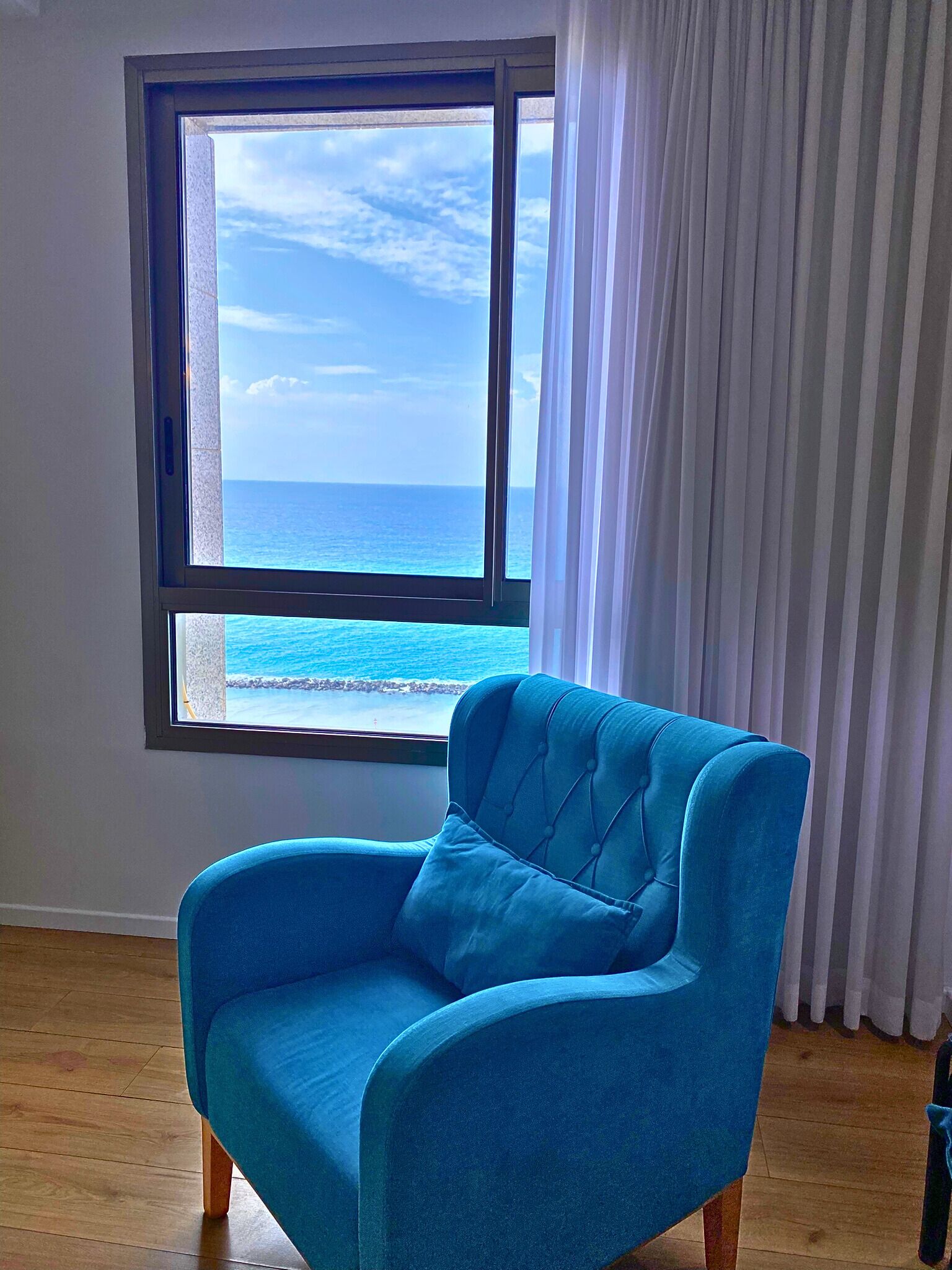A room with a large window offering a view of the ocean.