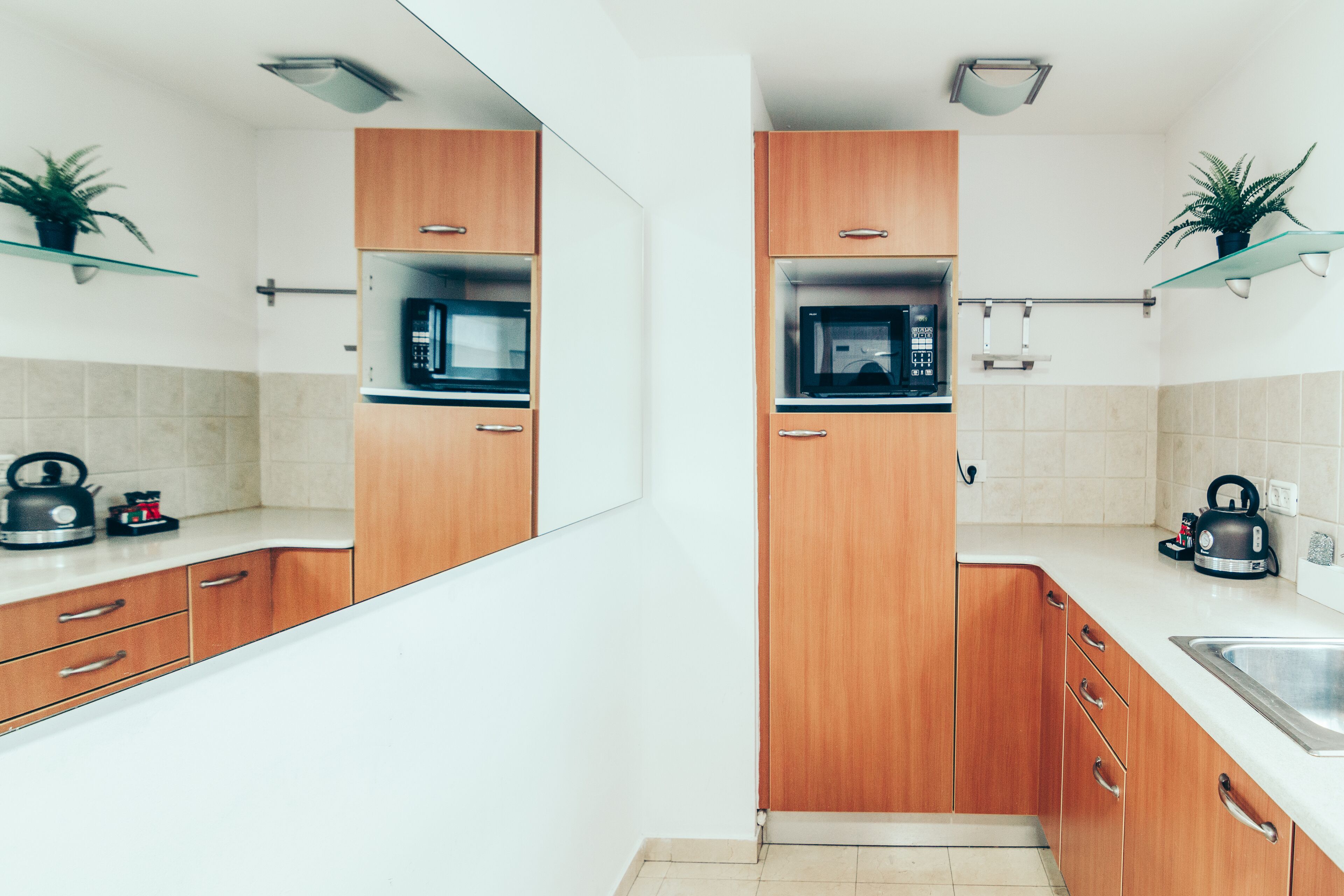 Une cuisine moderne avec des meubles en bois, un four à micro-ondes, une bouilloire et un évier.