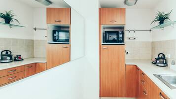 Une cuisine moderne avec des meubles en bois, un four à micro-ondes, une bouilloire et un évier.