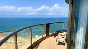 A balcony with a view of the ocean, a table, and chairs. - Almog Beach (Haifa)