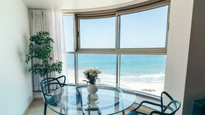 A round glass table with four chairs, a potted plant, and a vase with flowers. - Almog Beach (Haifa)