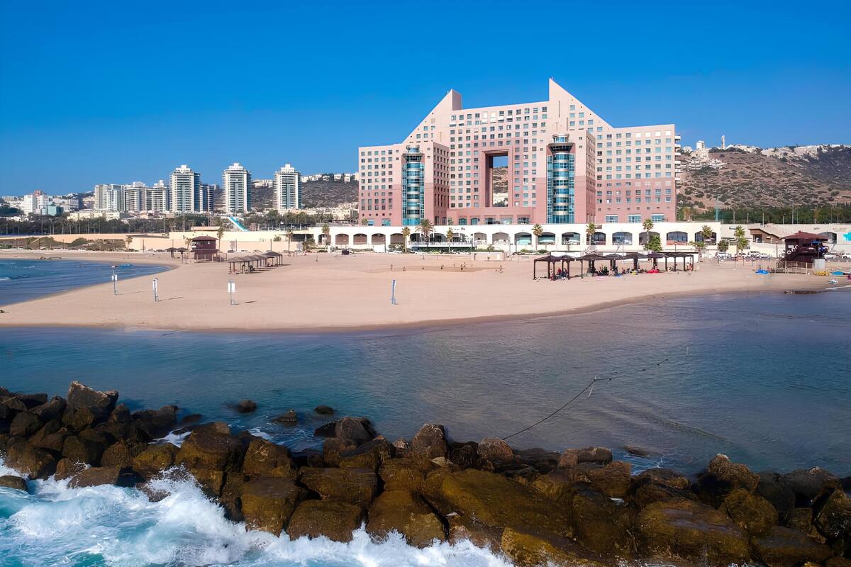 A hotel with a modern architectural design, a beachfront location, and a pool area.