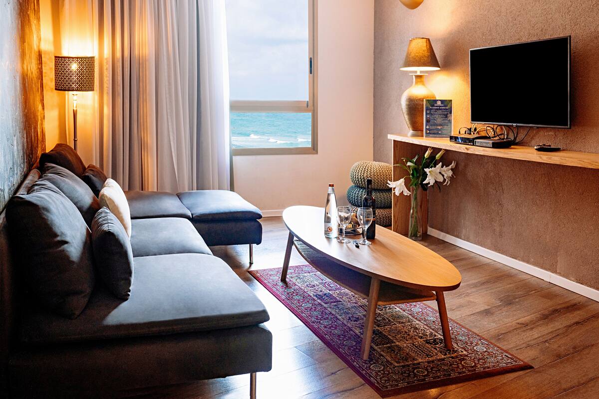 A modern living room with a sofa, a coffee table, and a TV mounted on the wall.