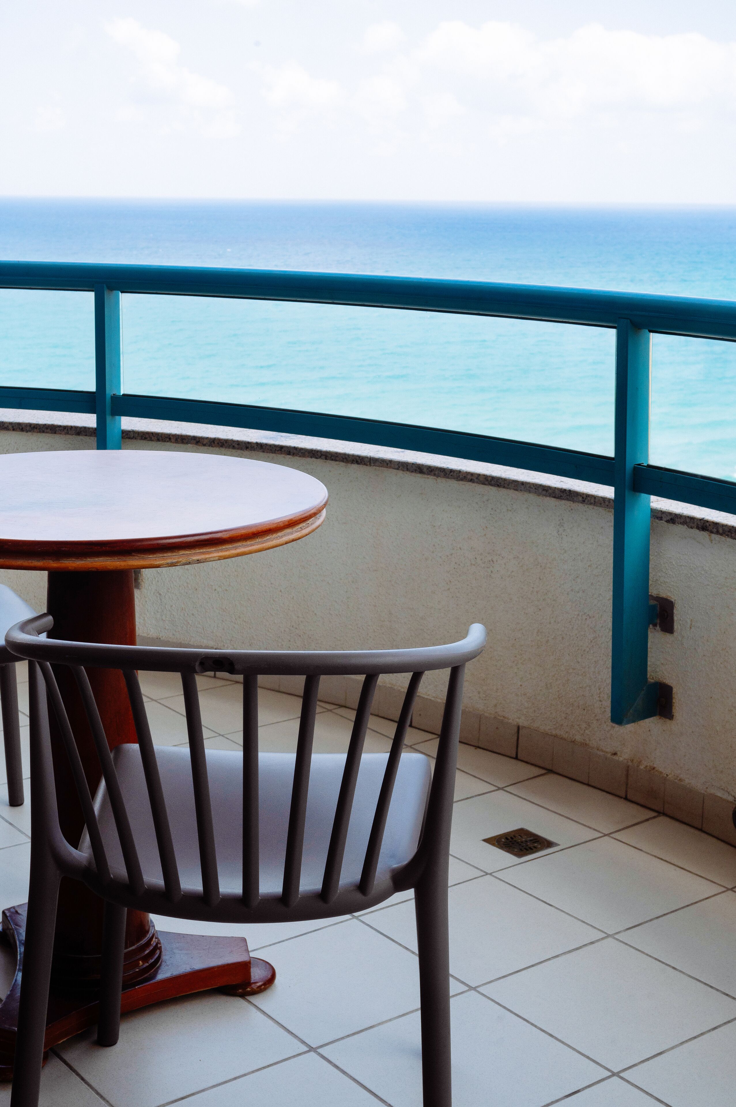 Varanda com mesa e cadeira, com vista para um corpo de água.