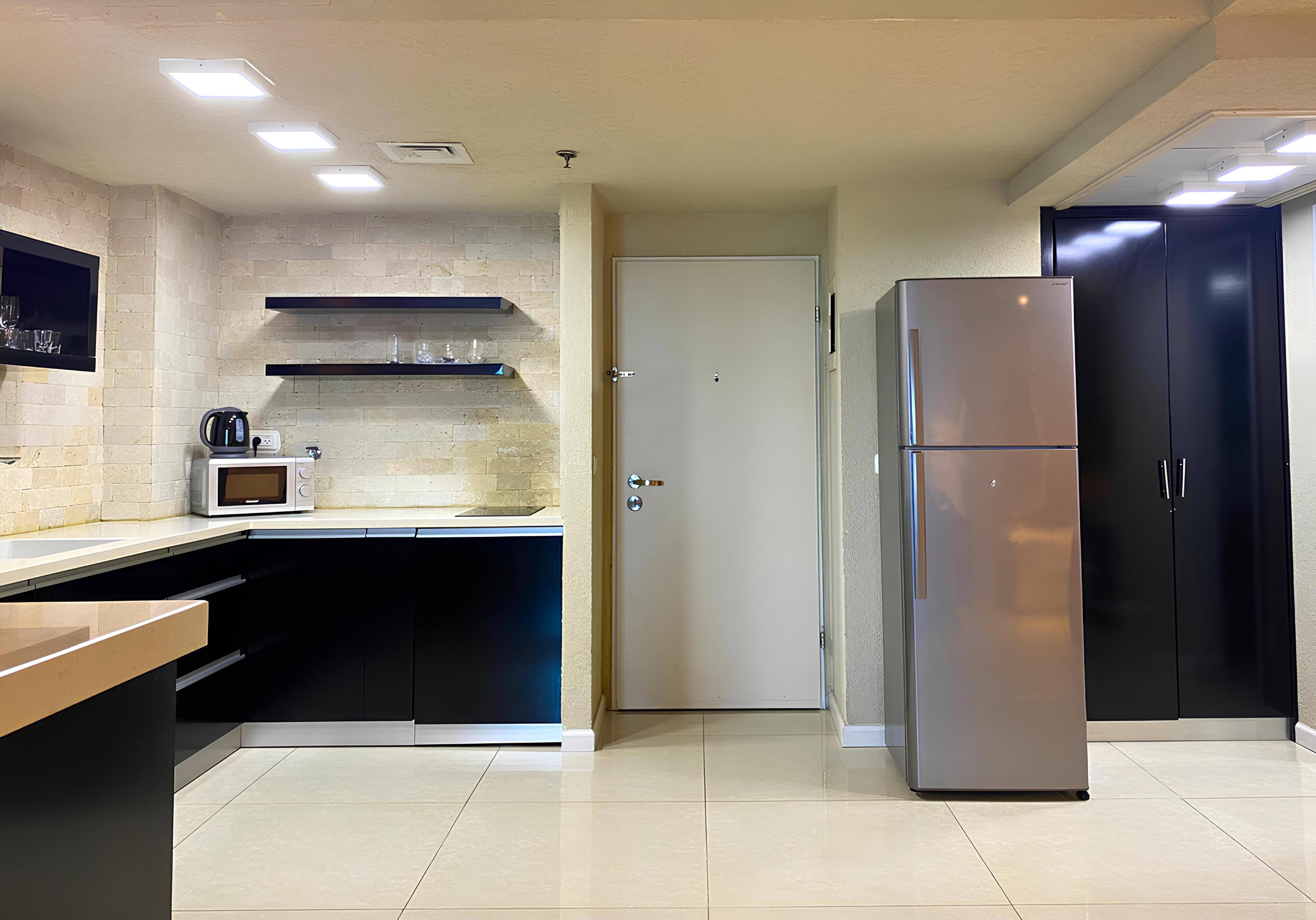 A modern kitchen with a microwave, toaster, and black cabinets.