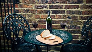 Une table avec une bouteille de vin, deux verres de vin et une miche de pain, le tout posé sur une planche en bois.