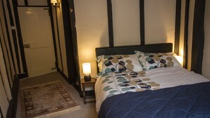 Une chambre à coucher avec un lit, une table de chevet, une lampe, une porte et un tapis à motifs.