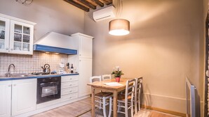 Una cocina con gabinetes blancos, una estufa y una mesa de comedor con sillas.