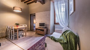 Un salón acogedor con una mesa de comedor de madera, un televisor y un sofá con una manta verde.