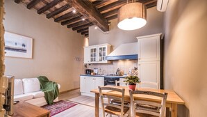 Una cocina compacta con armarios blancos, una mesa de comedor de madera y una alfombra roja.