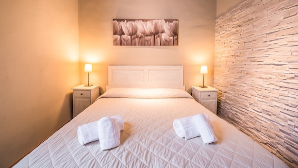 Una cama bien hecha, con dos toallas, un cabecero y una obra de arte colgada en la pared.