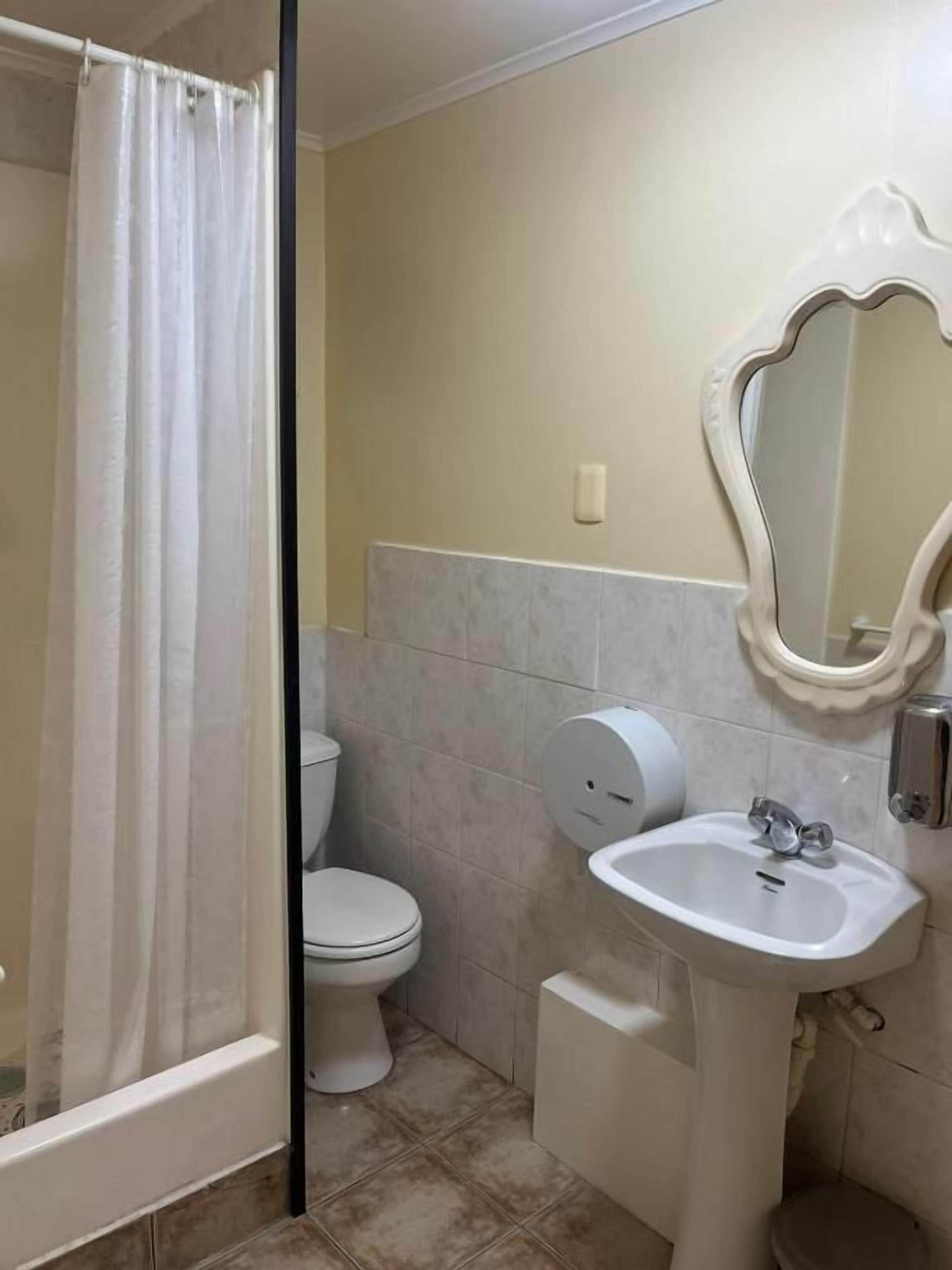 Une salle de bain équipée d’une douche, de toilettes, d’un lavabo et d’un miroir.