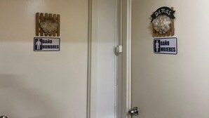Two doors with signs indicating 'BAÑO HOMBRES' and 'BAÑO MUJERES'. - Hostal Maipu Street (Punta Arenas)