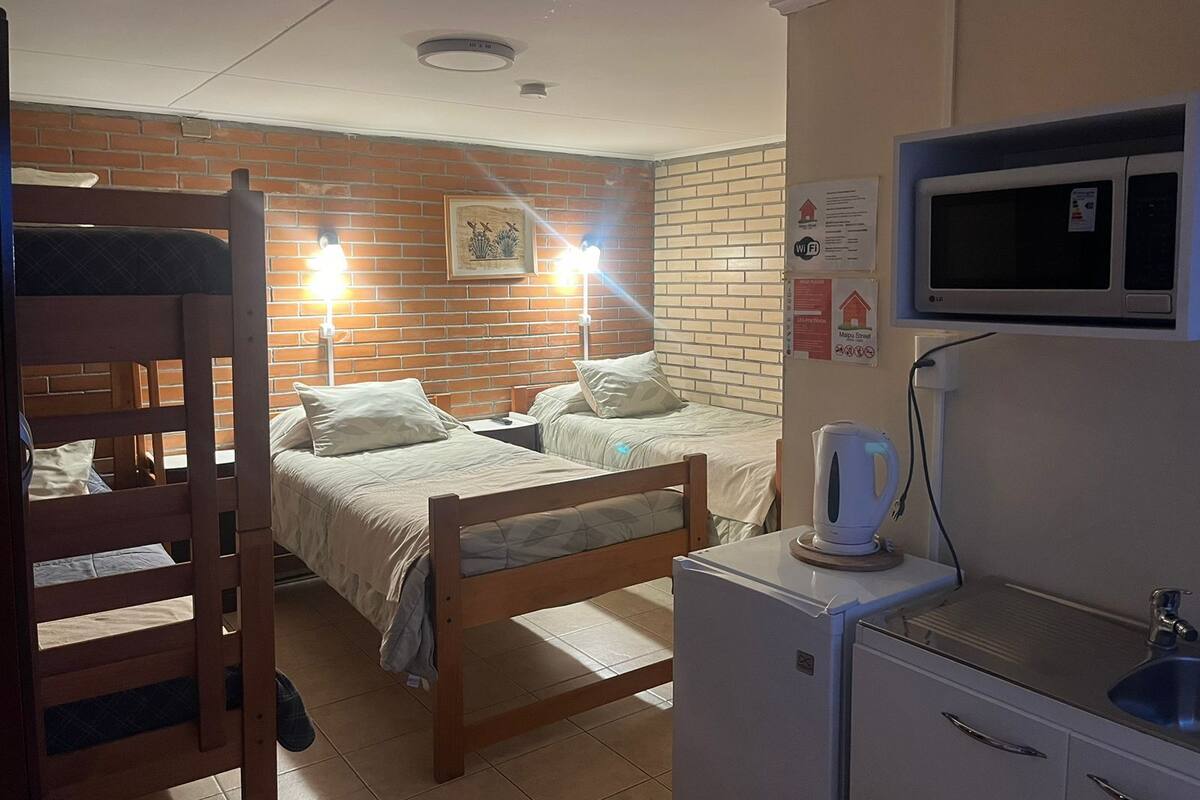 Ein Schlafsaalzimmer mit Etagenbetten, einer Mikrowelle, einem Wasserkocher und einem kleinen Kühlschrank.
