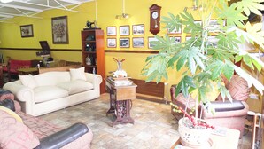 A living room with a white sofa, a wooden coffee table, a large potted plant, and a wall decorated with framed pictures. - Hostal Maipu Street (Punta Arenas)