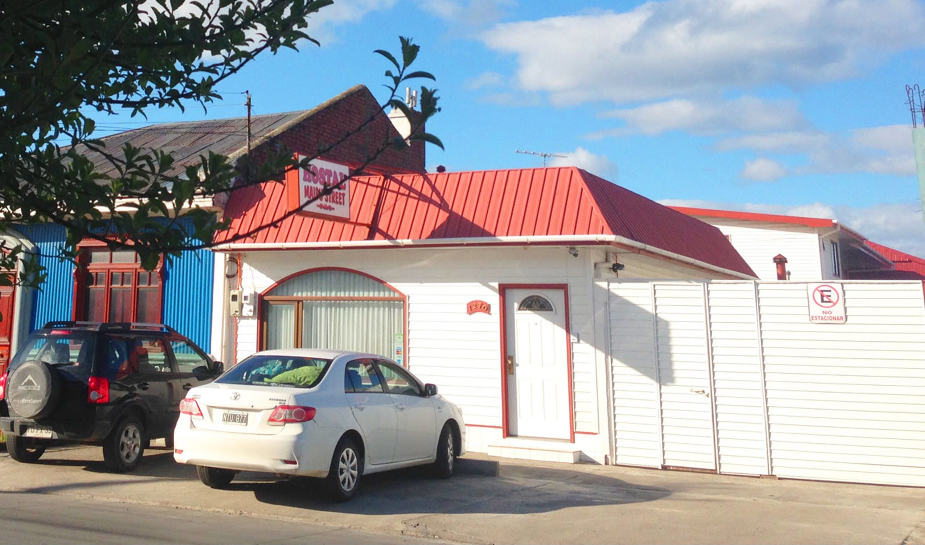 Un edificio bianco con tetto rosso, un'entrata per garage e un cartello con la scritta 'No estacionar'.