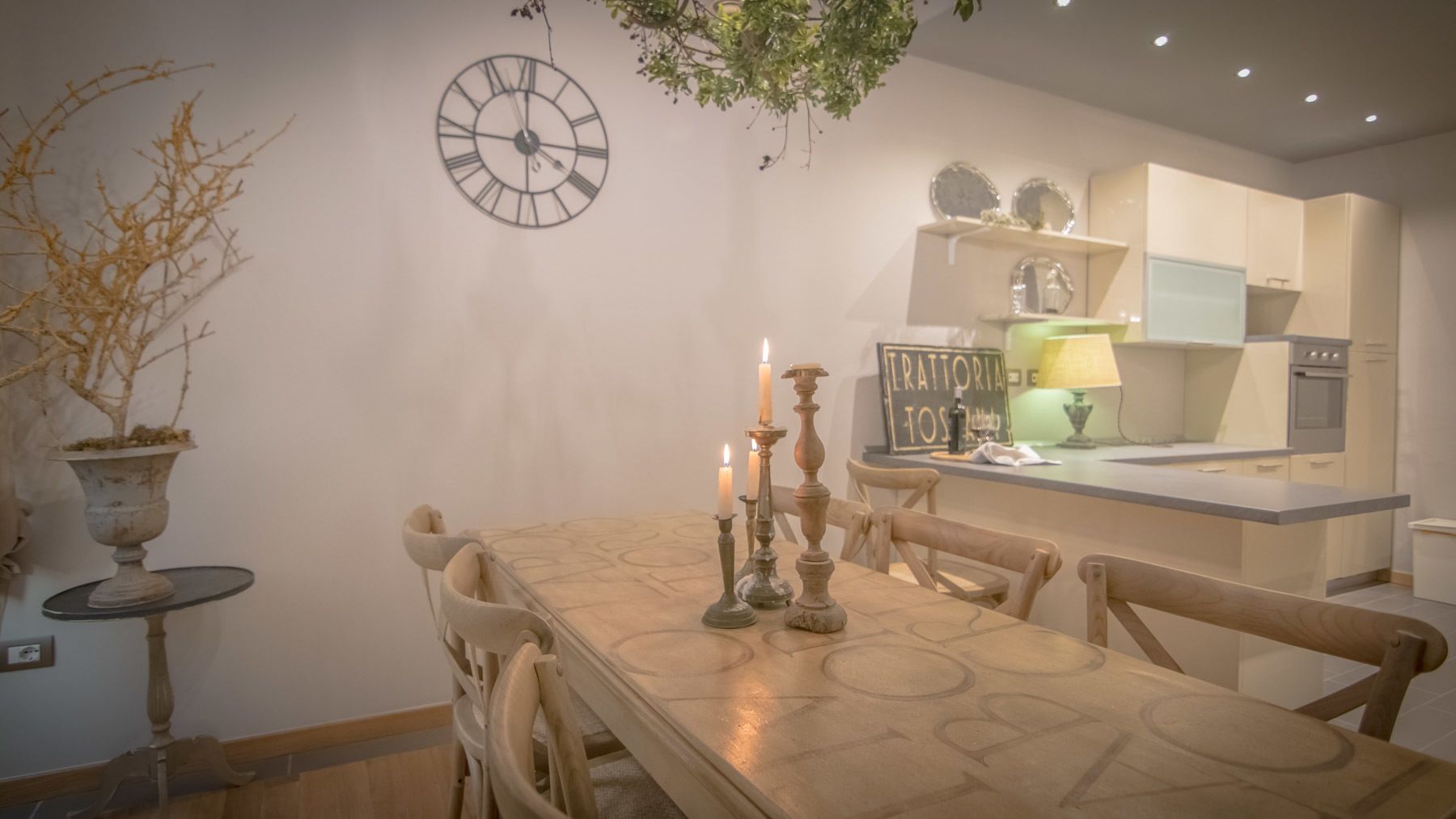 Een eetruimte met een tafel, stoelen, een klok en een plant in een pot.