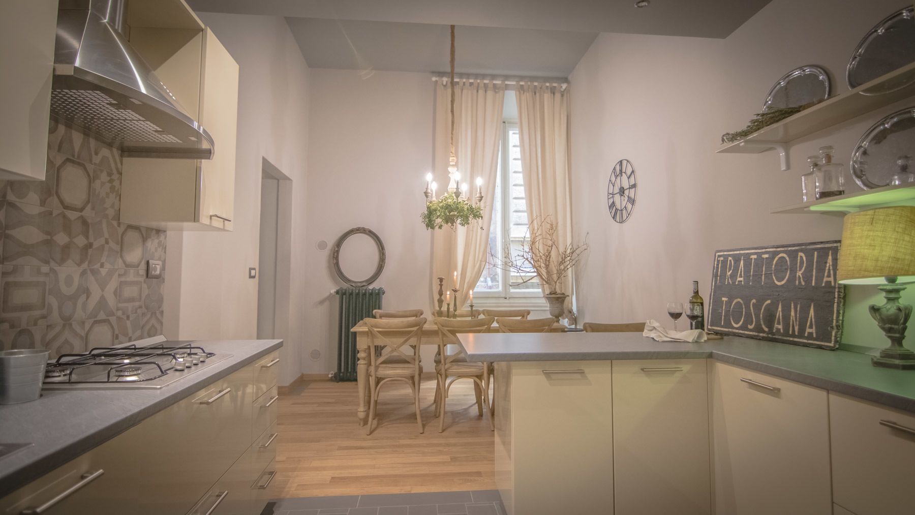 Una cocina moderna con una isla central, sillas de madera, una mesa de comedor y una araña.