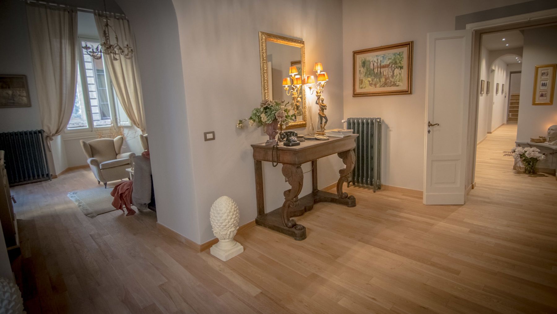 A well-lit hallway with a vintage-style console table, a large mirror, and a radiator.