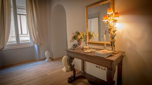 A room with a wooden console table, a mirror with a gold frame, a telephone, a vase with flowers, and a statue. - Breathtaking 4BD Apt 5min Walk to Duomo (Florence)