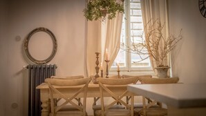 A dining area with a round mirror, a radiator, a window with curtains, and a potted plant. - Breathtaking 4BD Apt 5min Walk to Duomo (Florence)