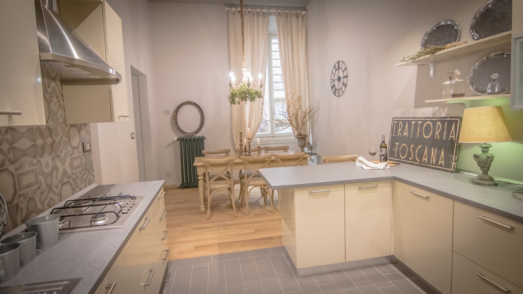 Cocina compacta con estufa a gas, mesa de comedor de madera y un letrero en una pizarra.