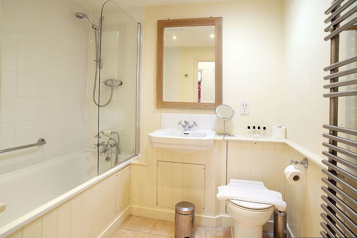 A bathroom with a bathtub, shower, sink, toilet, and a mirror.