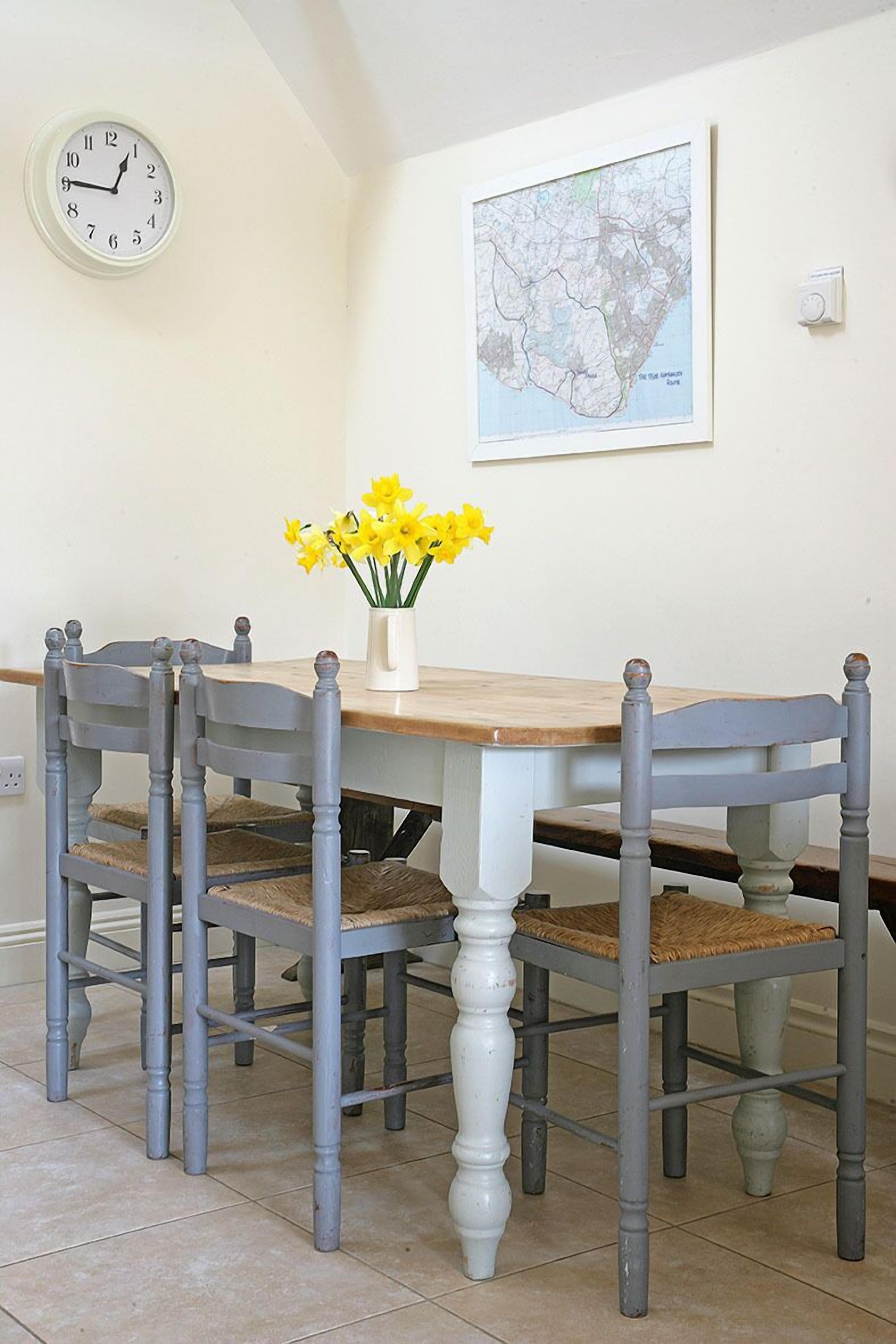 A dining table with four chairs, a clock, and a map on the wall.