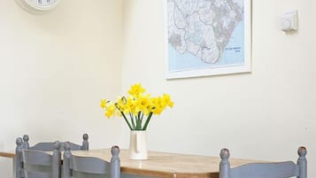 A dining table with four chairs, a clock, and a map on the wall.