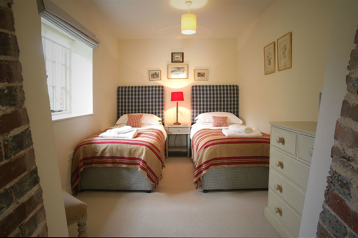 A bedroom with two beds, a nightstand, a lamp, and a dresser.