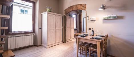 A dining area with a wooden table and chairs, a built-in cabinet, and a window with a view of a building.