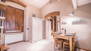 Ein Essbereich mit Holztisch und -stühlen, weißen Schränken und einer großen Holztür.