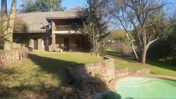 Enjoy a tranquil retreat with a balcony overlooking a lush lawn and a pool.
