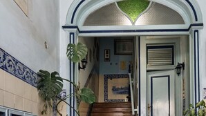 A staircase with a wooden handrail leading to a door with a blue and white trim. - 1924 (Lisbon)