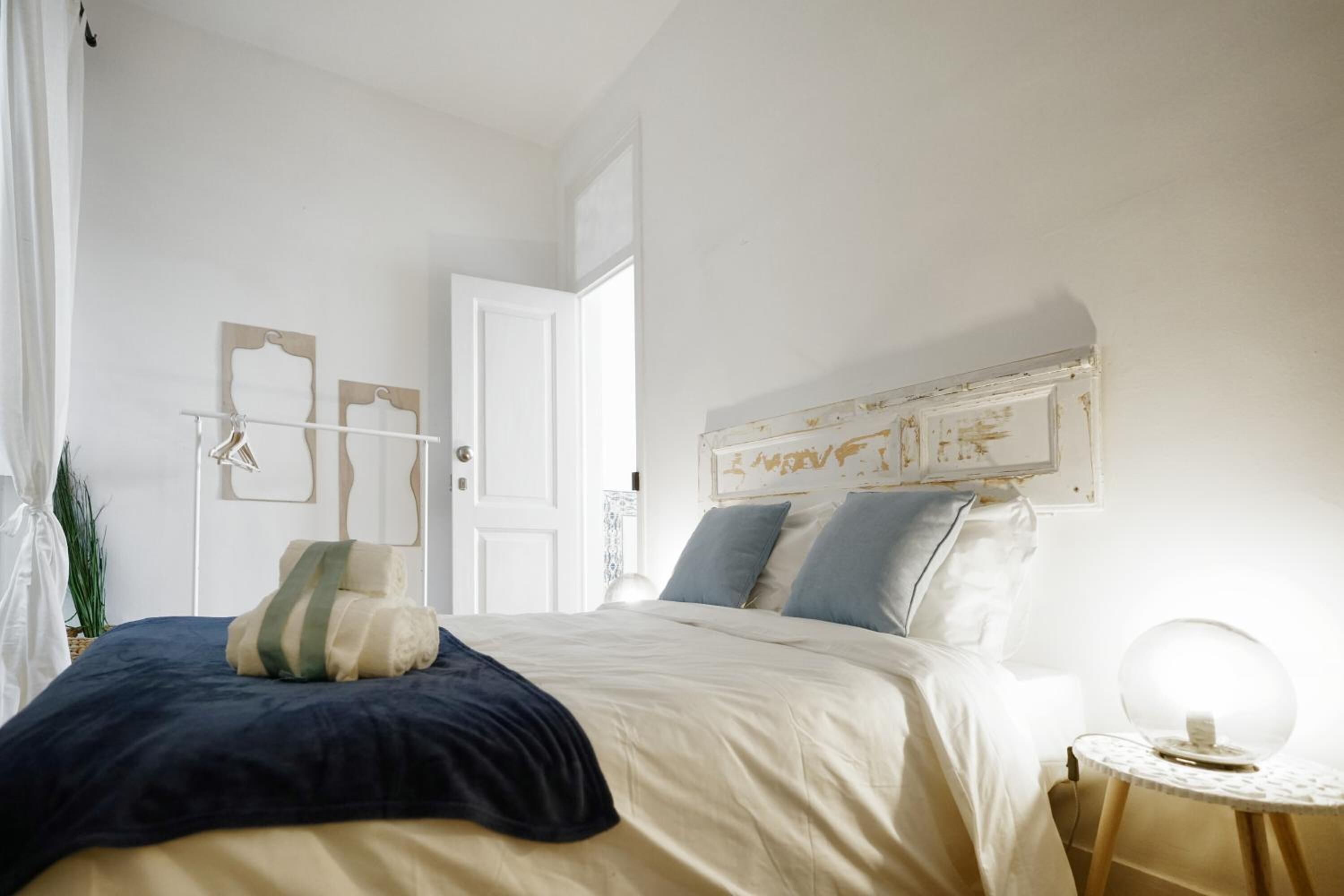 A bedroom with a bed, bedside table, and a wall-mounted light fixture.