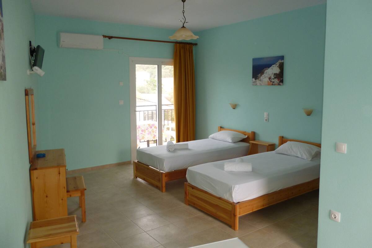 A room with two wooden beds, a desk, and a chair.
