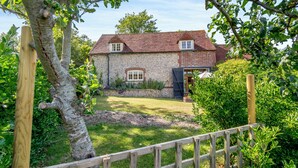 A stone house with a red roof, a wooden fence, and a garden. - Beachy Barn (Eastbourne)
