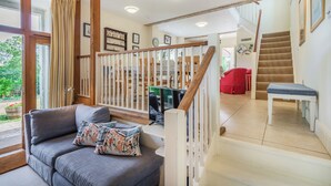 A spacious living area with a grey sofa, a television, and a staircase leading to another room. - Beachy Barn (Eastbourne)