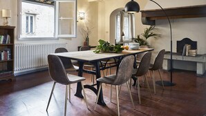 A dining area with a wooden table, six chairs, a floor lamp, and a bookshelf. - Best Location Rooftop and Pitti Palace View (Florence)