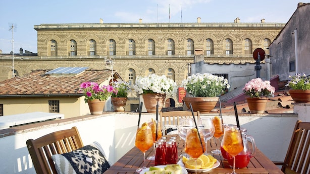 A rooftop terrace with a table set for dining, potted flowers, and drinks. - Best Location Rooftop and Pitti Palace View (Florence)