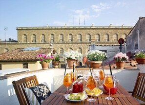A rooftop terrace with a table set for dining, potted flowers, and drinks. - Best Location Rooftop and Pitti Palace View (Florence)