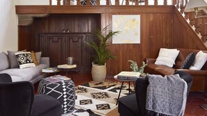 A spacious living room with a high wooden staircase, a chandelier, and a world map on the wall. - Best Location Rooftop and Pitti Palace View (Florence)