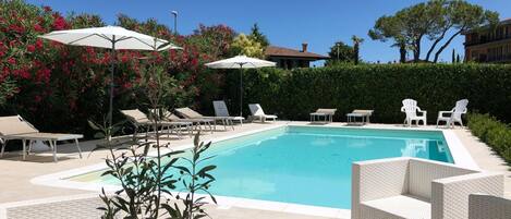 En säsongsöppen utomhuspool, parasoller och solstolar