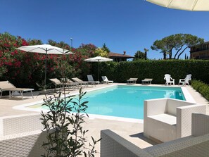 A swimming pool with lounge chairs and umbrellas, surrounded by greenery and a hedge. - Bed & Breakfast da Beatrice (Sirmione)
