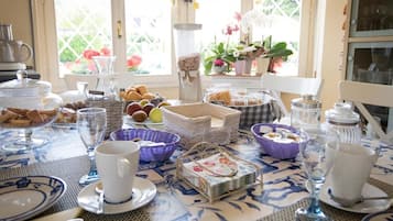 Et morgenbord dækket med tallerkener, kurve og glas, med udsigt til en have gennem et vindue.
