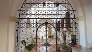 A wrought iron gate with intricate designs, leading to a courtyard with potted plants and a view of a building with balconies. - B&B Casa Resci (Tricase)