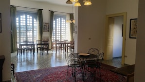 A spacious dining area with a large window, a chandelier, and a red patterned rug. - B&B Casa Resci (Tricase)